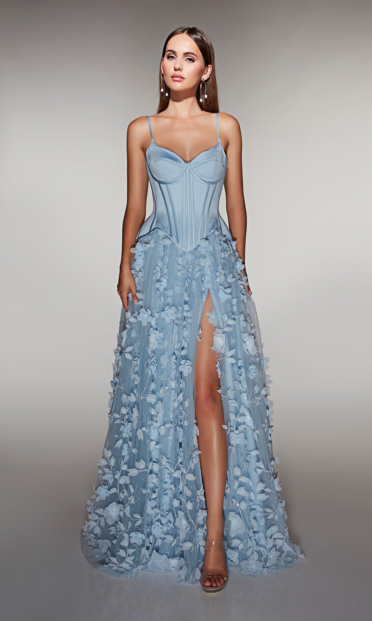A woman poses against a neutral background wearing the Alyce 62072—a light blue, strapless long formal dress with 3D floral-lace appliques, corset bodice, and high slit.